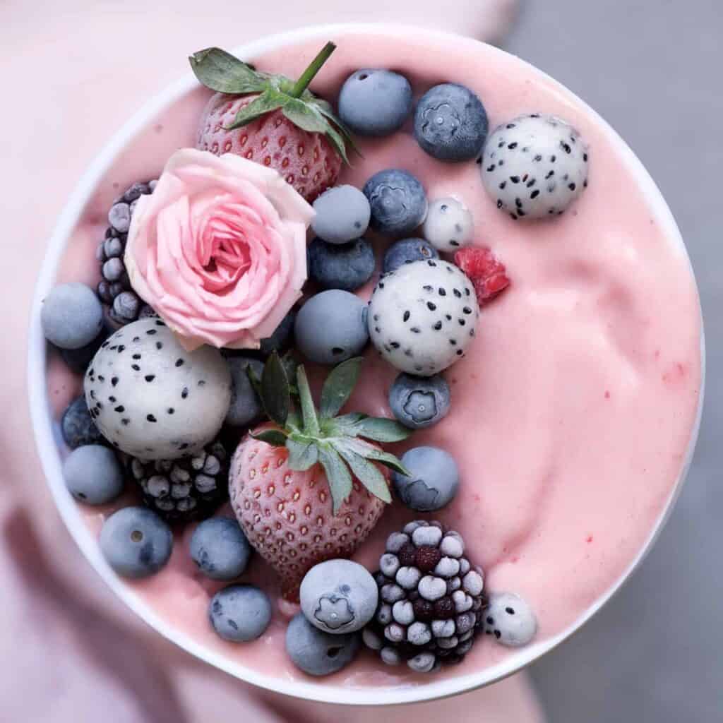 Vegan strawberry smoothie served in a bowl topped with frosty fruit