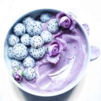 Purple smoothie with dragon fruit balls and edible flowers