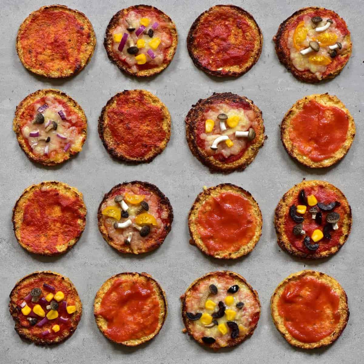 Baked mimi pizzas topped with tomato sauce and some with cheese corn and mushrooms
