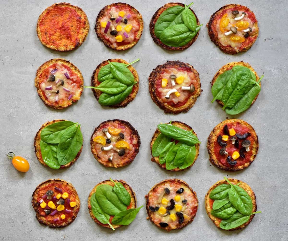 Baked mimi pizzas topped with tomato sauce and some with cheese and corn and some with spinach leaves