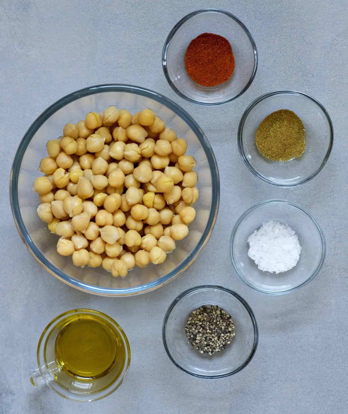 A bowl of chickpeas and small bowls with different spices 