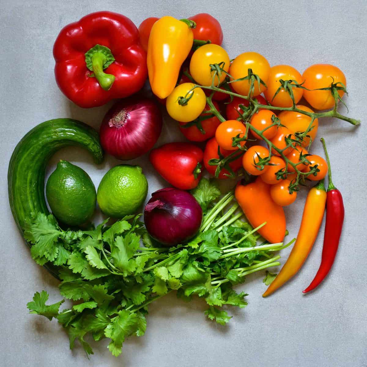 Colorful vegetables including peppers cherry tomatoes onion cucumber lime and parsley 