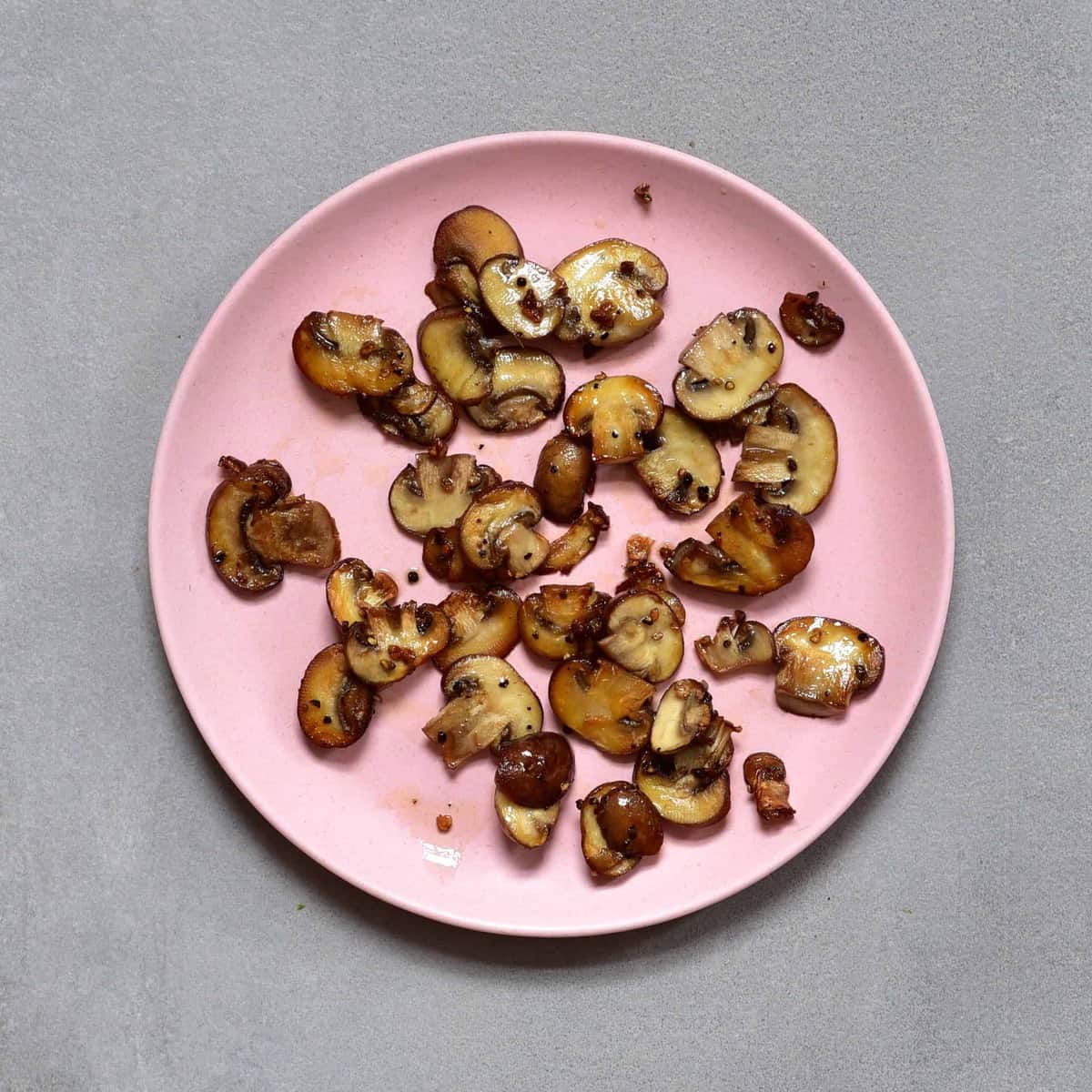 Cooked mushroom slices on a pink plate