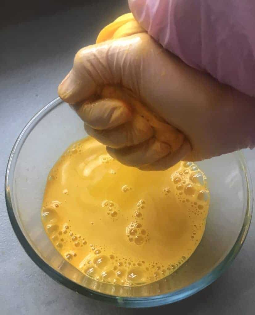 Squeezing a nut milk bag with blended turmeric and ginger juice into a bowl 