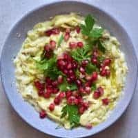 moutabal eggplant dip in bowl and topped with herbs and pomegranate