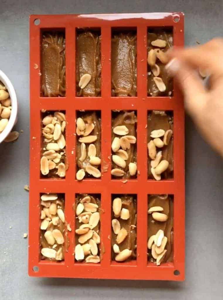 sprinkling nuts into homemade vegan snickers bars