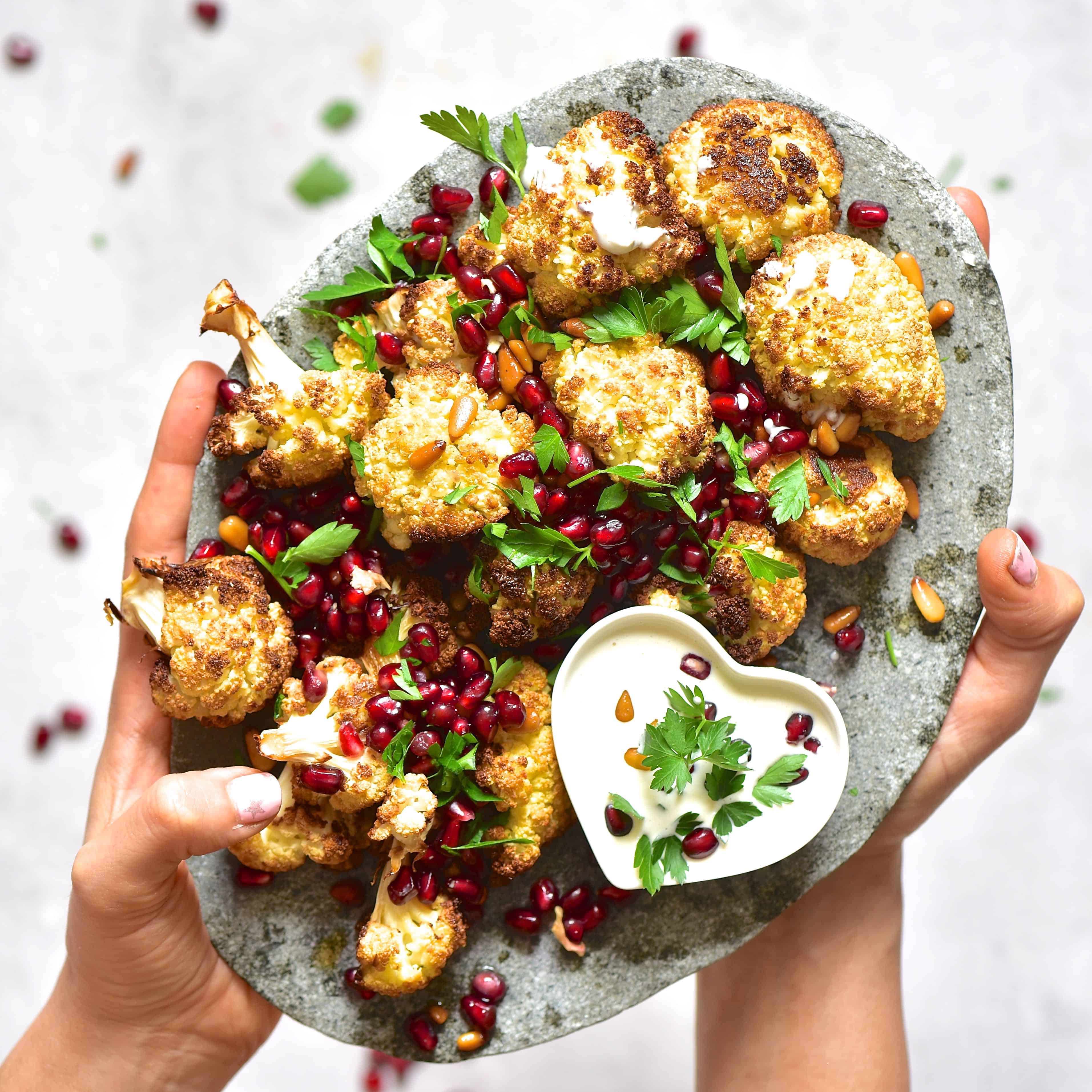 vegetarian baked tahini cauliflower wings with pomegranate and pine nuts.