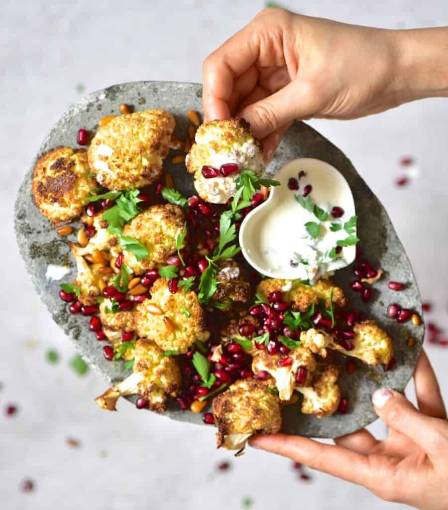 vegetarian baked tahini cauliflower wings with pomegranate and pine nuts.