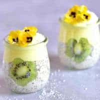 Two jars with overnight oats mango yogurt flower shapes cut from kiwis and edible flowers