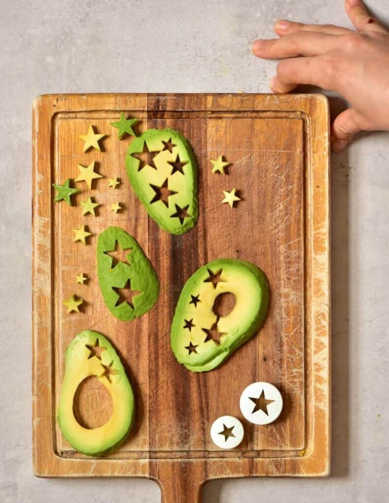 Cutting out starts from avocado slices on a wooden board