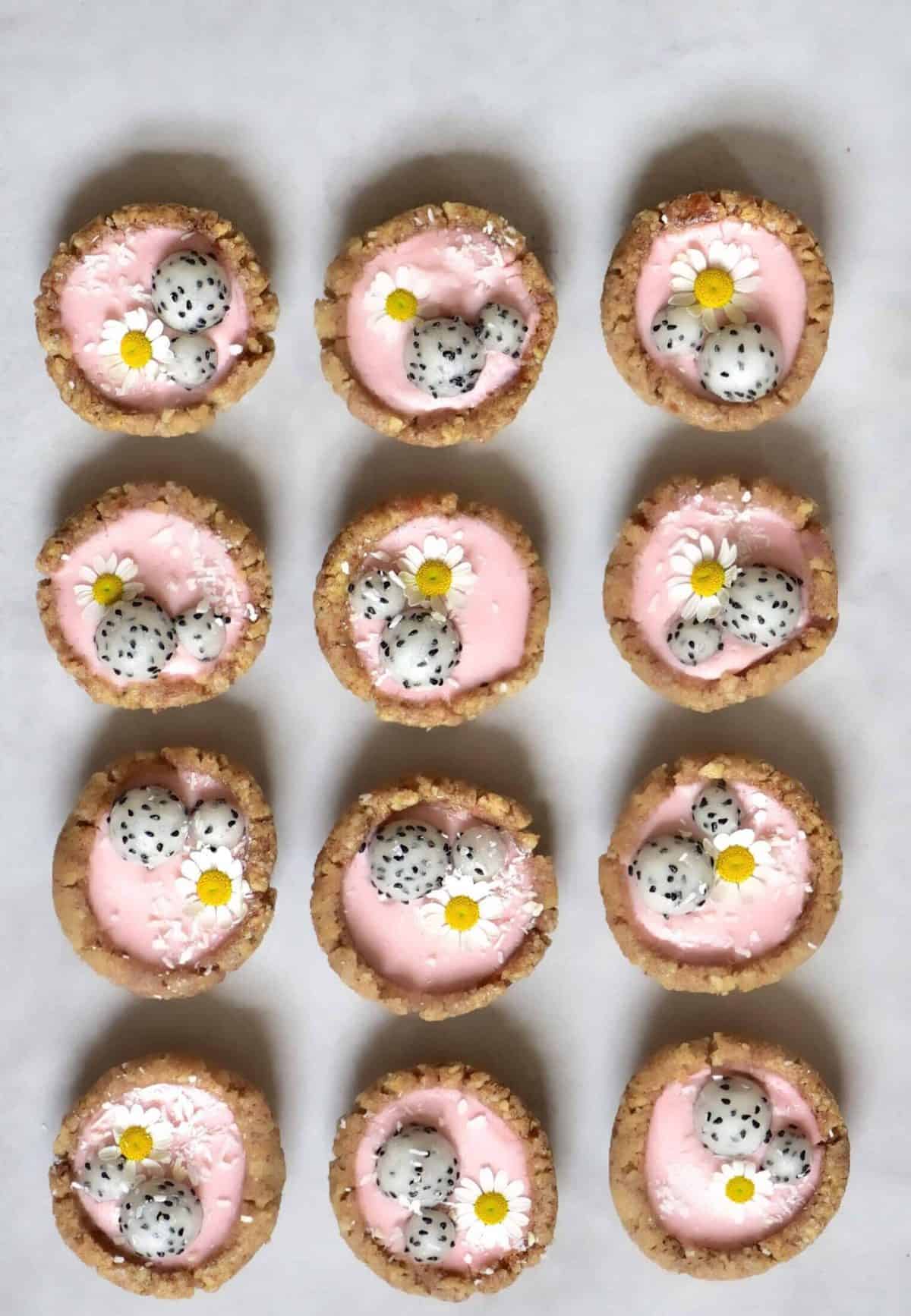 Mini pink tarts with dragonfruit balls, coconut, and daisy flowers