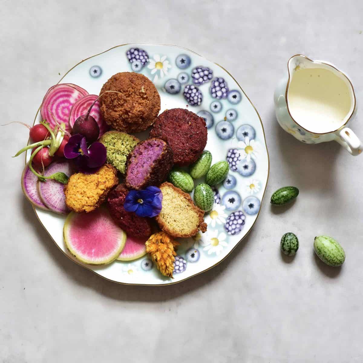 Rainbow falafel with veggies, yogurt tahini dip and edible flowers as part of a mezze platter