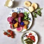 Rainbow falafel with veggies, yogurt tahini dip, pita bread and edible flowers