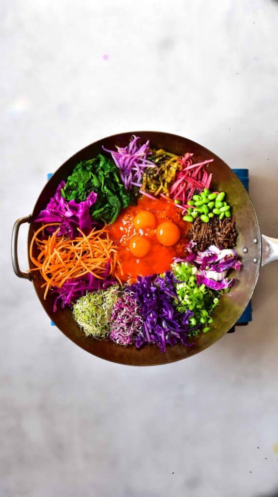 Rainbow veggies and egg yolks on top of rice for a homemade bibimbap