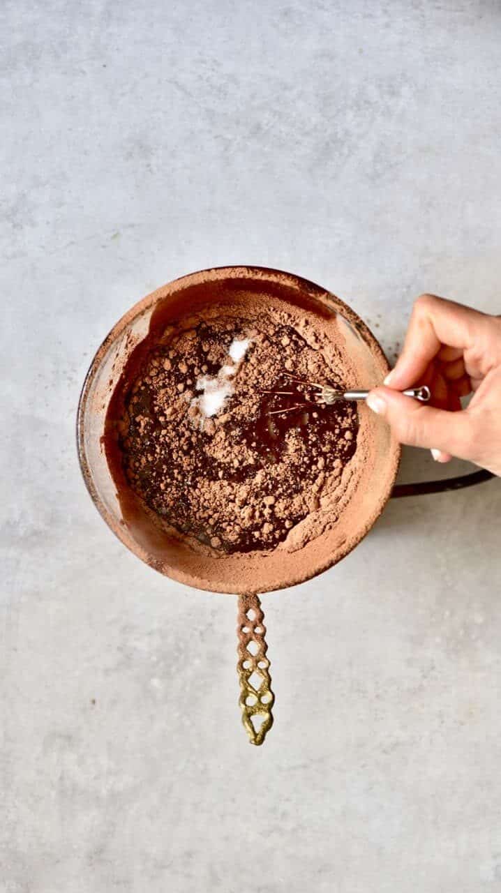 Mixing cacao powder with coconut oil over a double boiler 