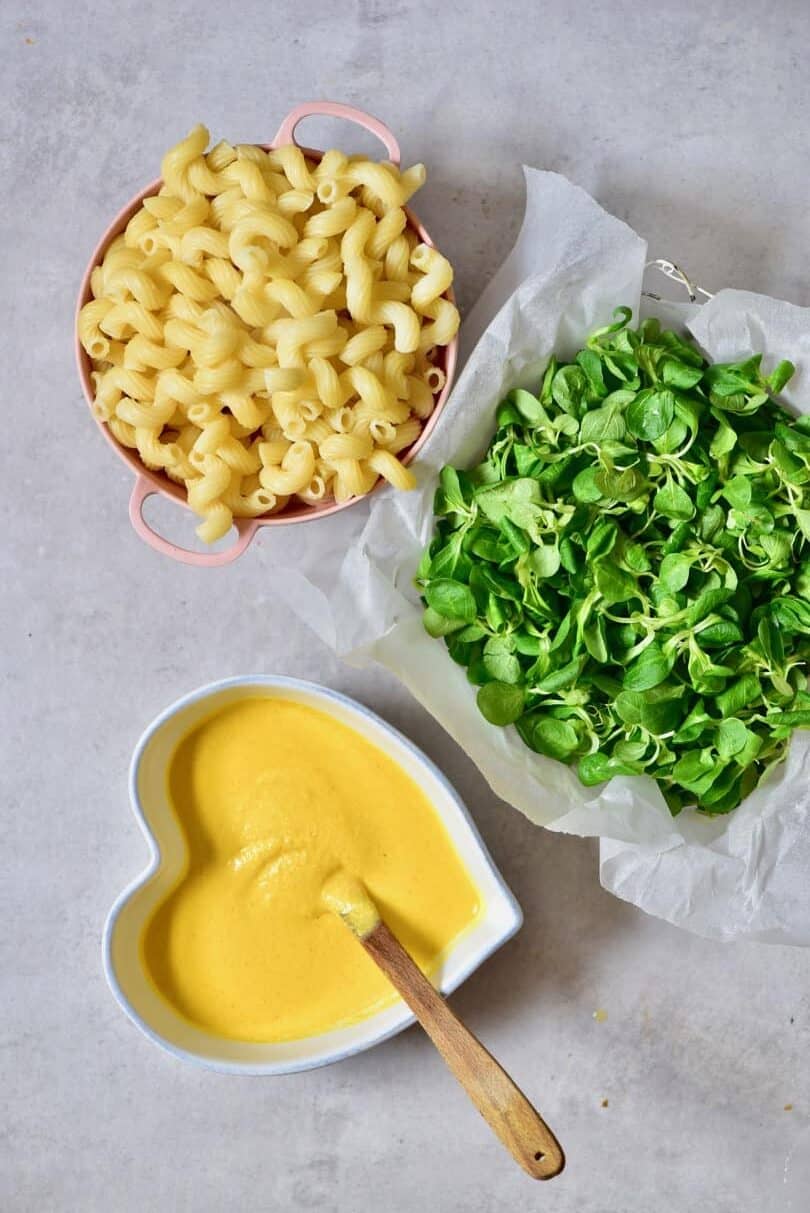 Boiled pasta, watercress salad and vegan mac and cheese sauce in a bowl