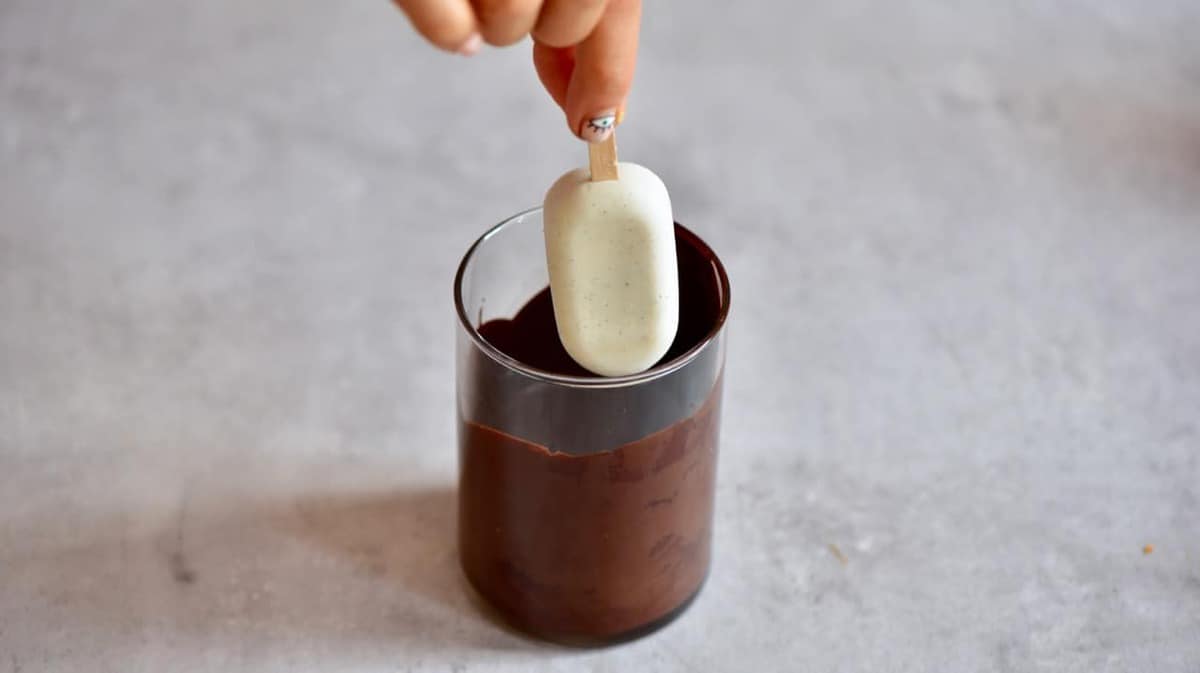 Homemade magnum ice cream being dipped in dark chocolate 
