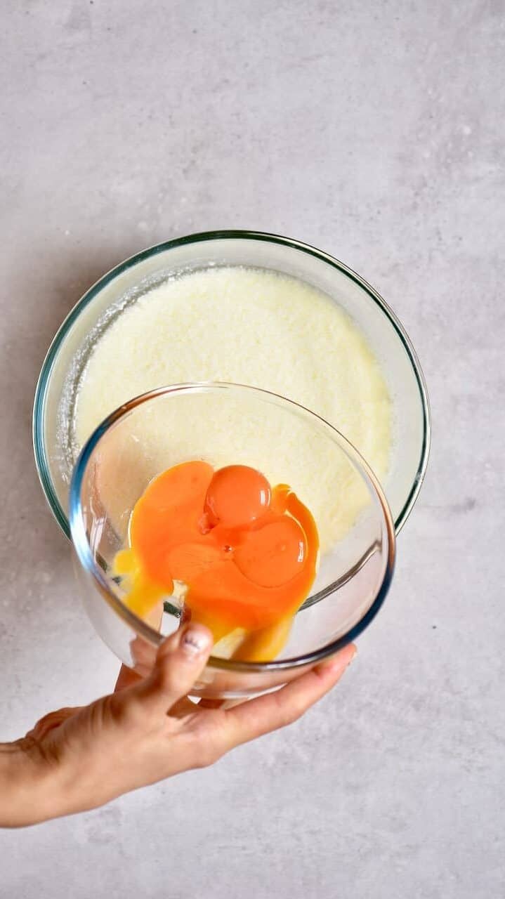 Adding egg yolks into a batter mixture in a bowl