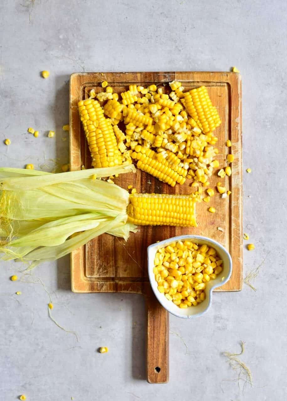 chopped corn on the cub on a wooden chopping board
