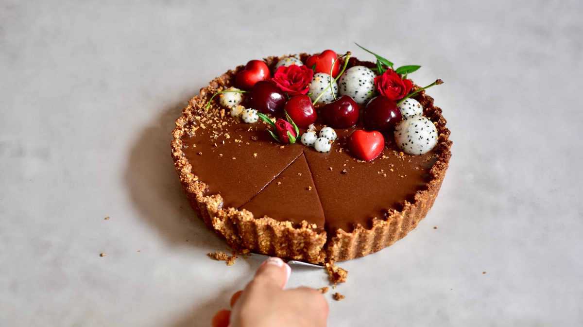 cutting a slice out of the refined sugar free Vegan chocolate cherry ' black forest' tart 