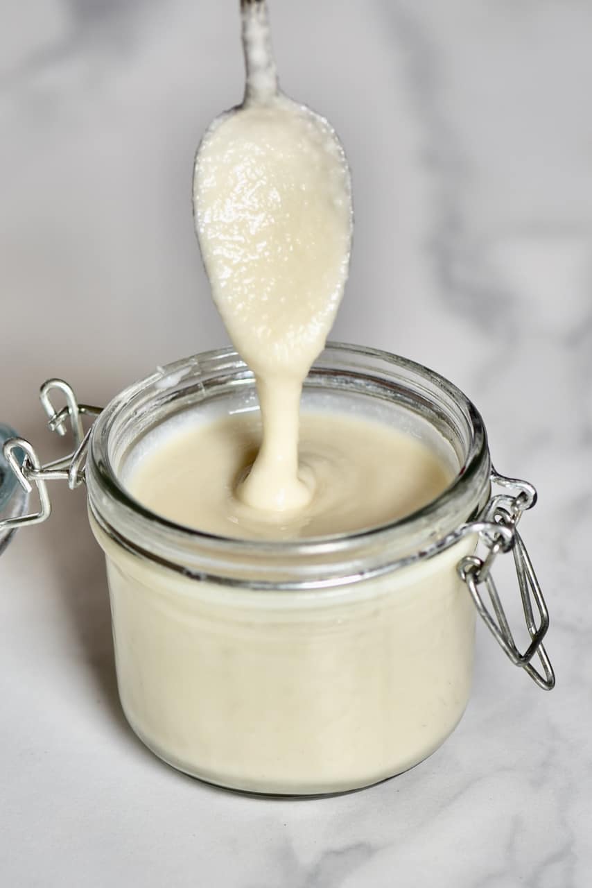 a spoon dripping coconut butter inside a coconut butter jar 