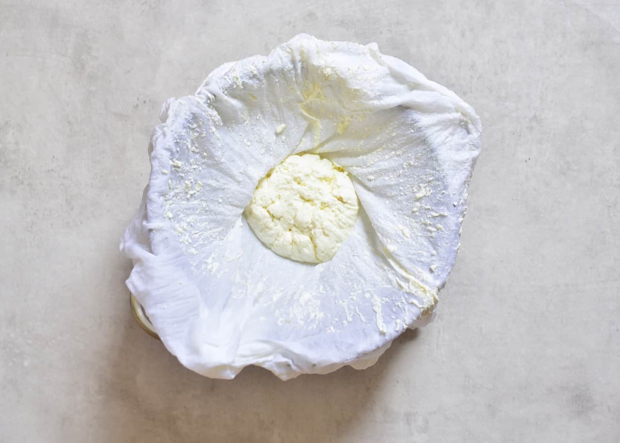strained ricotta cheese inside a layer of cheesecloth