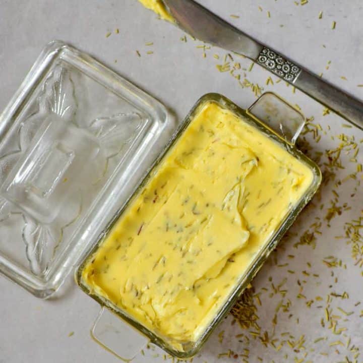 Homemade compound butter in a glass square bowl and a knife on the side