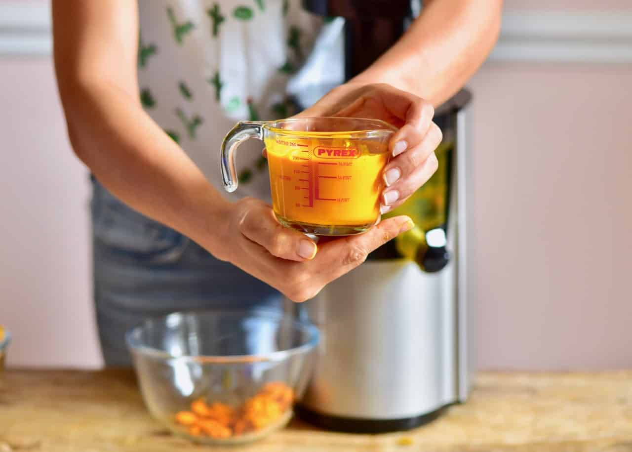 Freshly juiced turmeric and ginger juice in a measuring cup