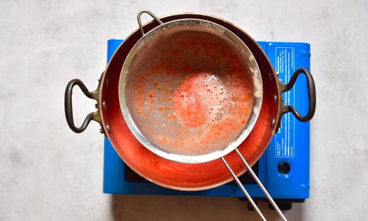 Sieving tomato juice into a pot