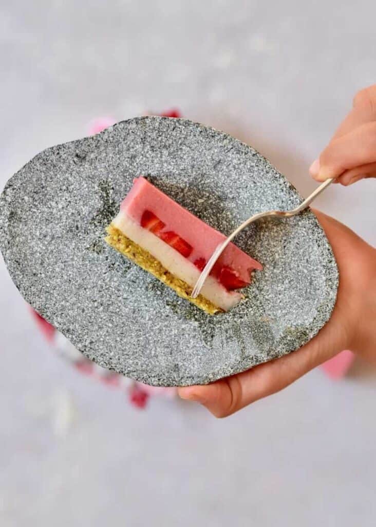 a slice of two-layer easy vegan strawberry tart on a stone plate