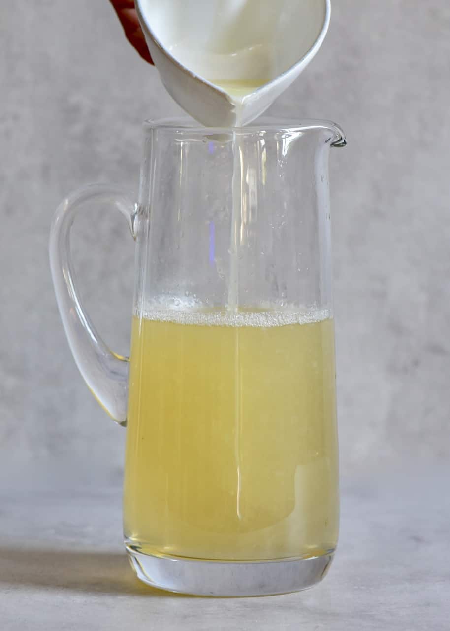 pouring lemon juice and sugar syrup into a large glass jug