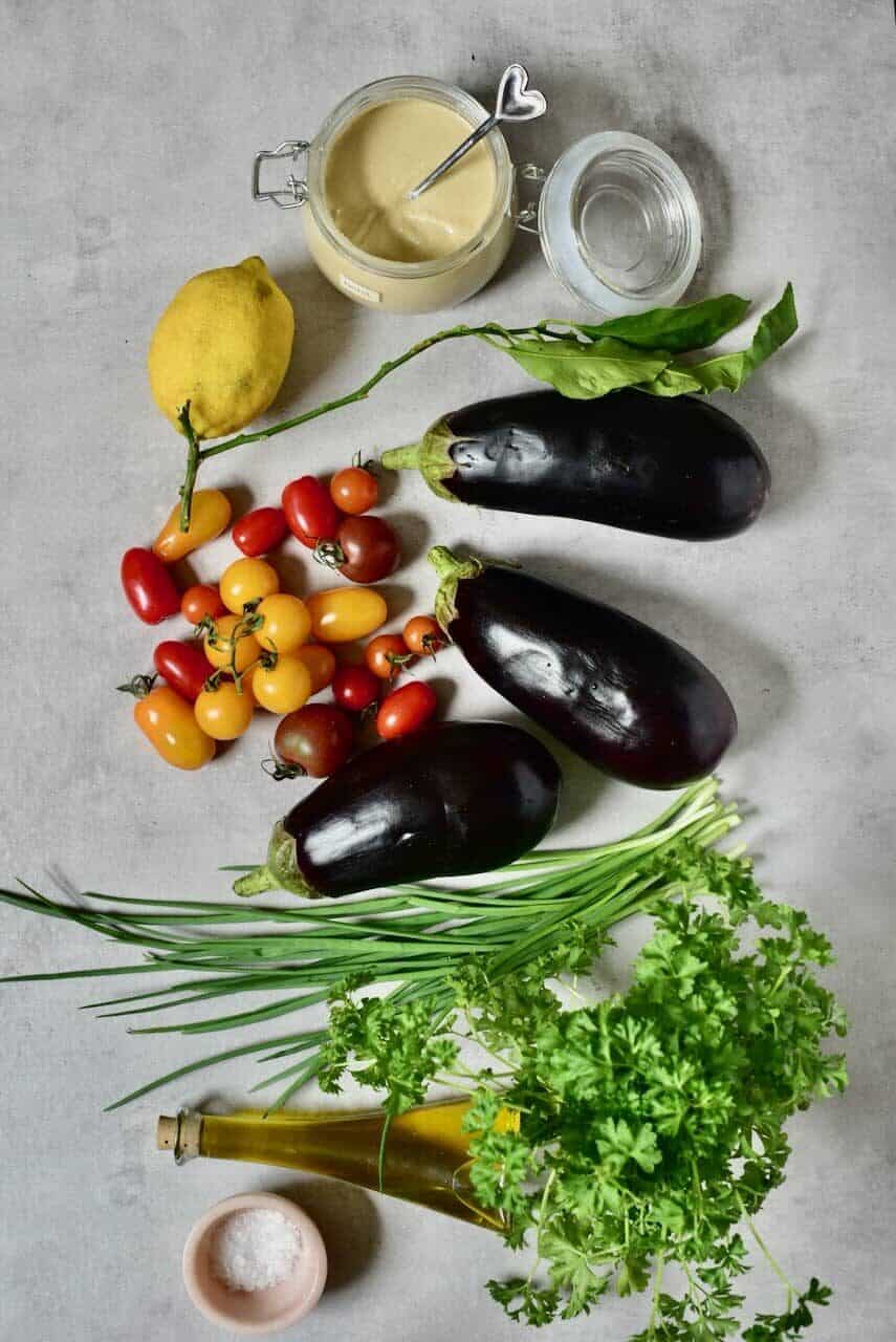 the ignredients for simple, healthy smoky eggplant dip (baba ganoush) with tahini, tomatoes, lemon juice, olive oil, and herbs.