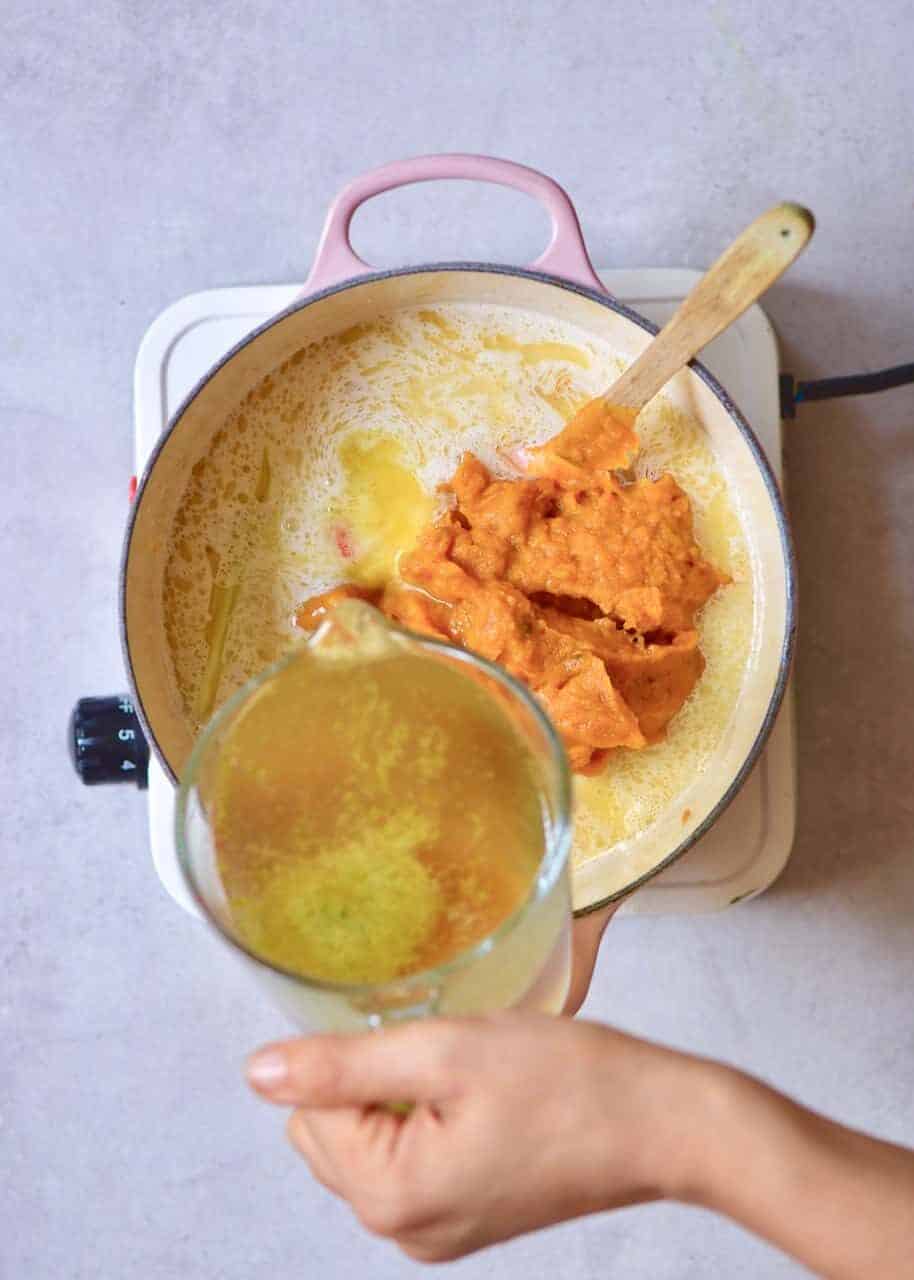 homemade pumpkin puree being added to coconut curry pumpkin soup. vegan