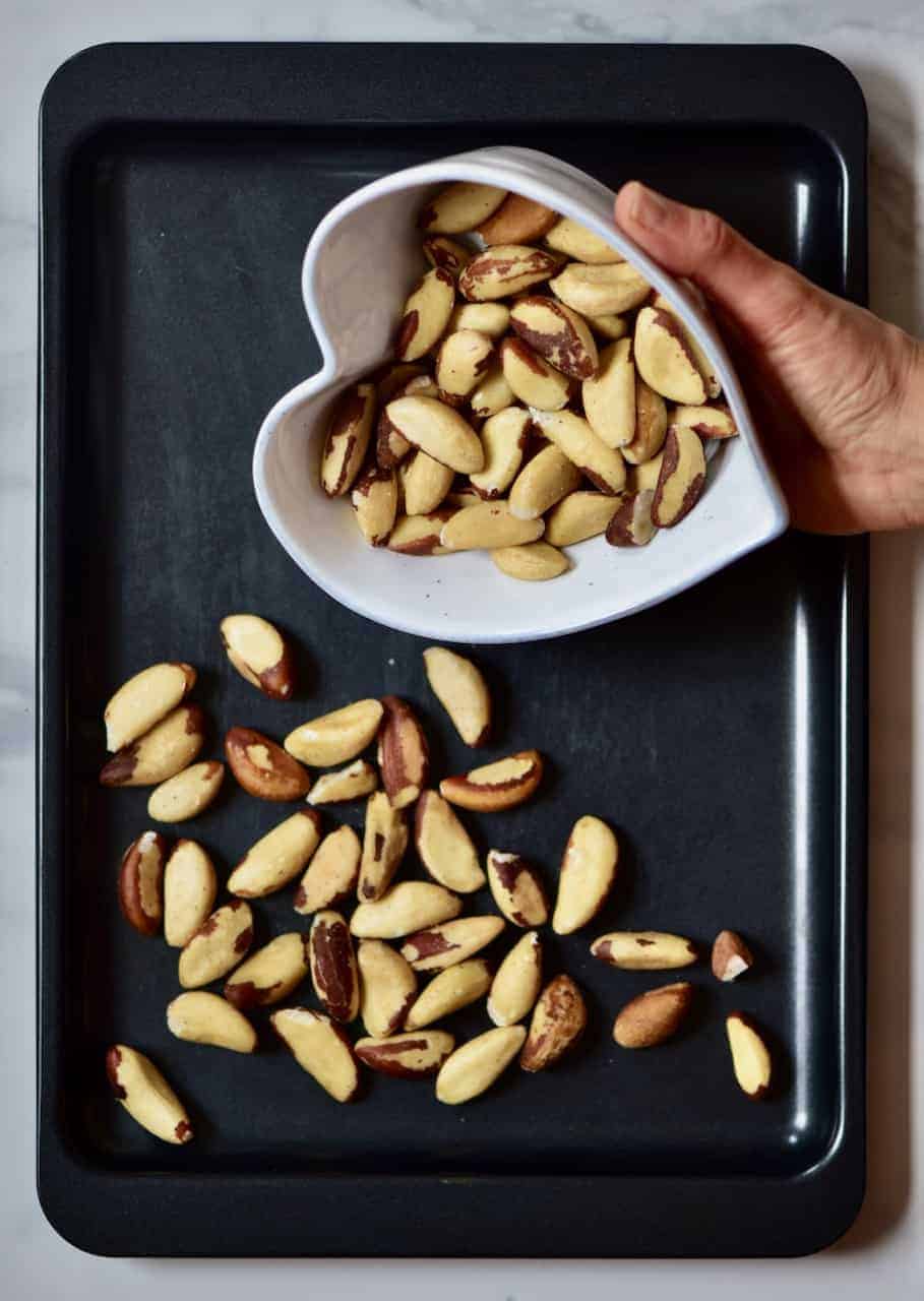 pouring brazil nuts in a baking tray