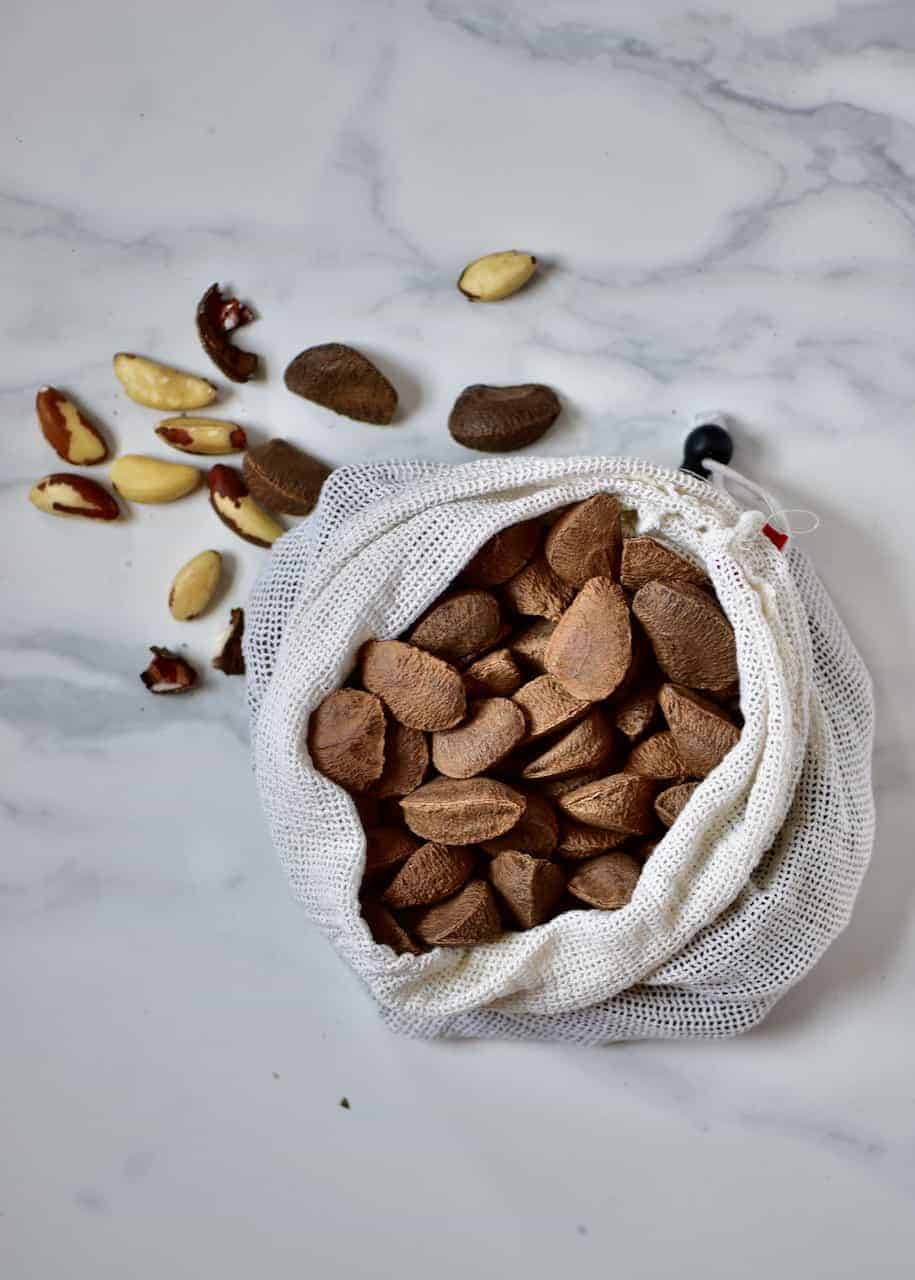 a bag of unshelled brazil nuts and some shelled nuts next to it