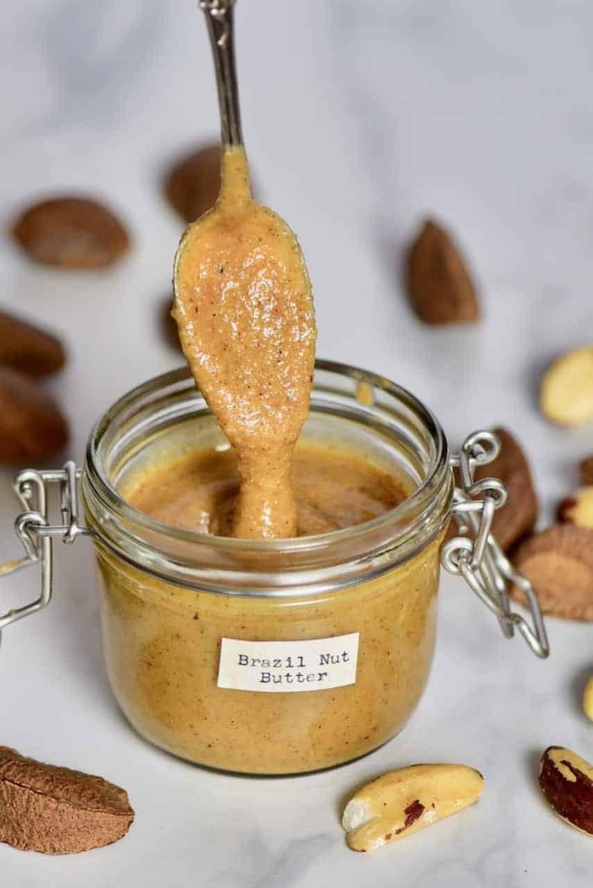 spoonful of brazil nut butter dripping over a jar with the butter