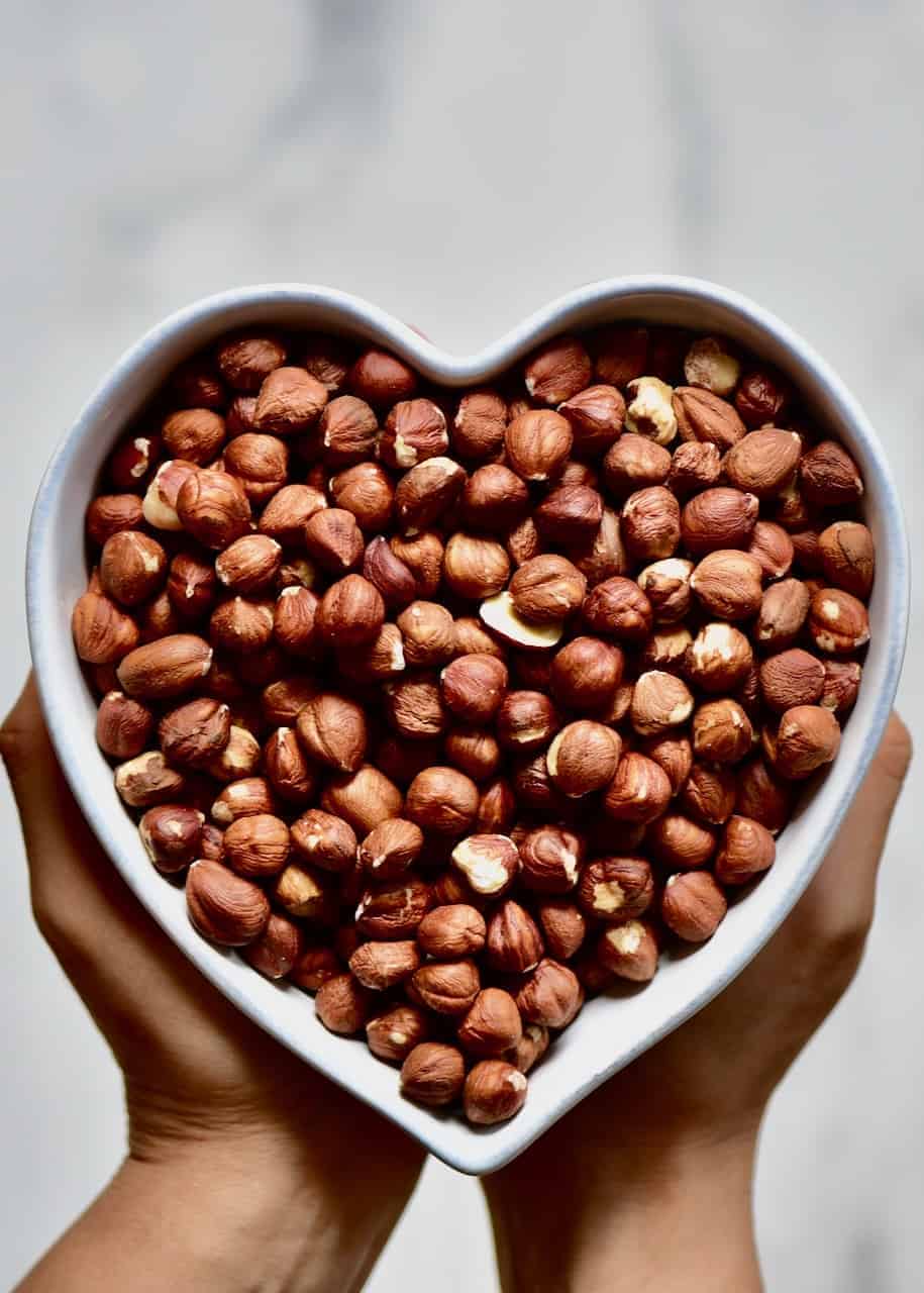 a heart-shaped bowl filled with hazelnuts 