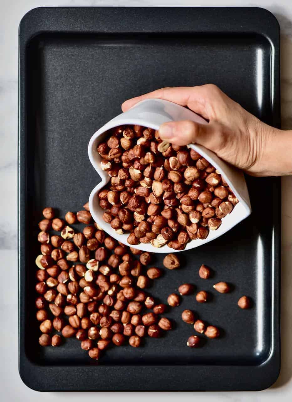pouring hazelnuts in a baking tray