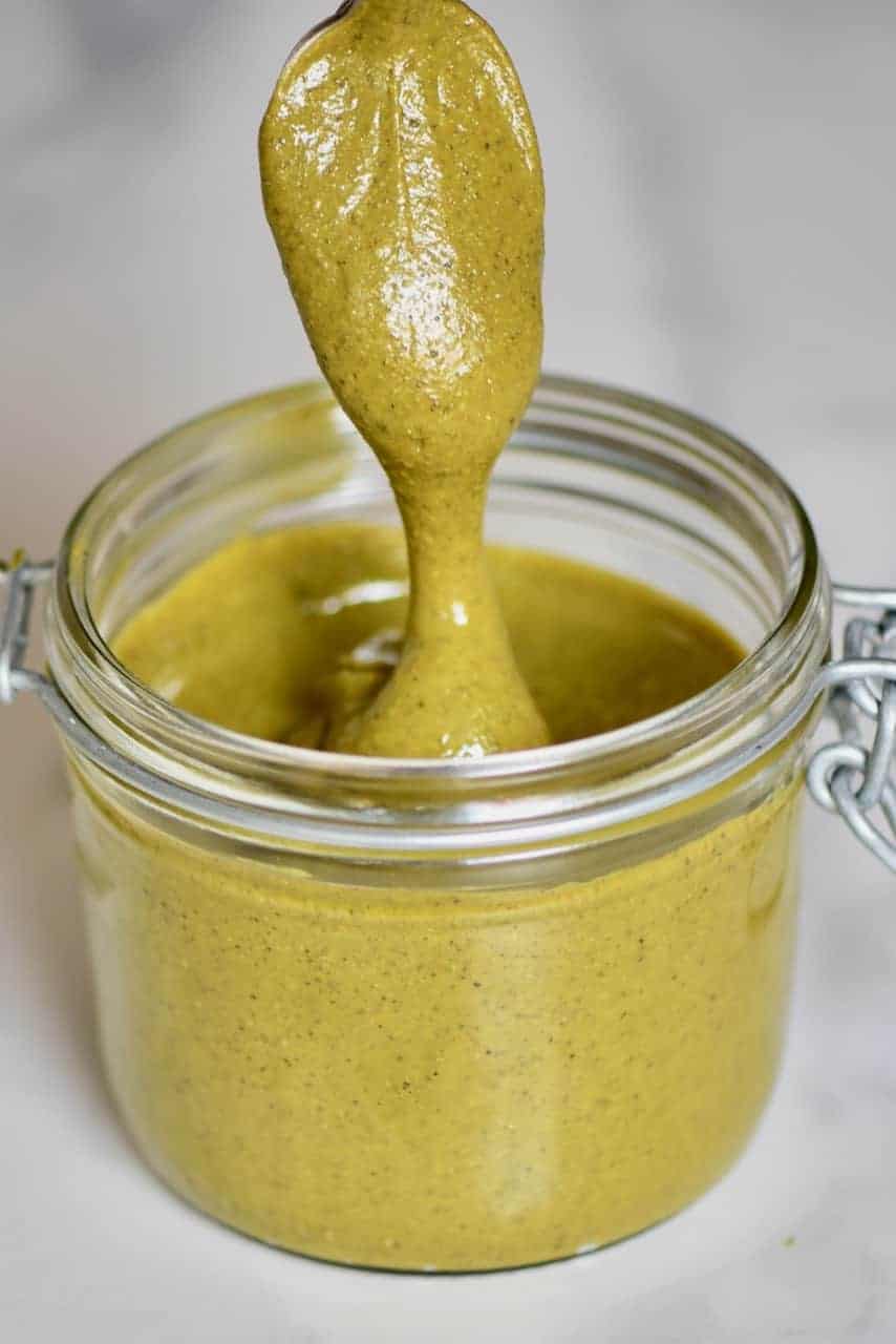spoonful of pistachio butter dripping over a jar