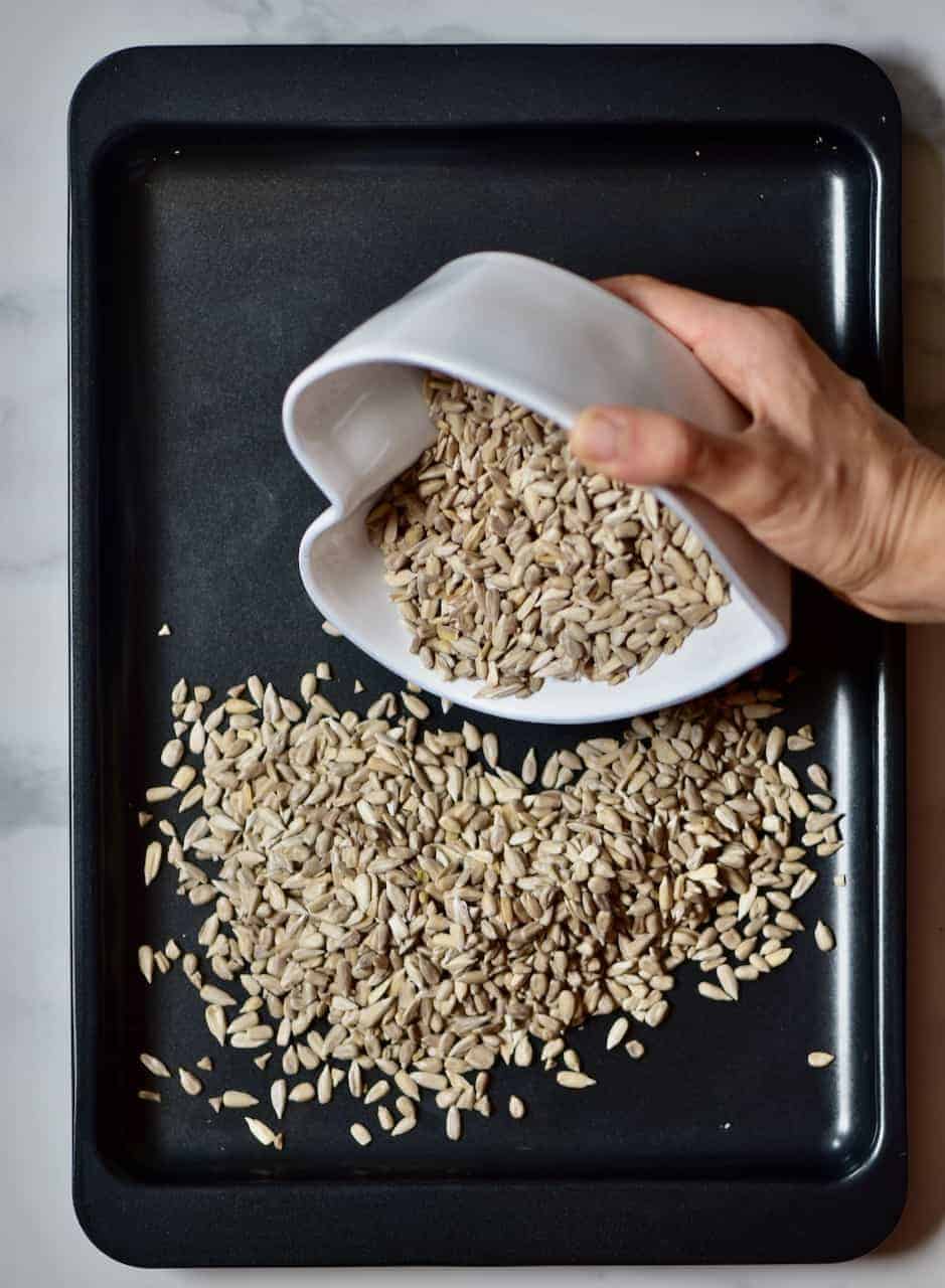 Pouring sunflower seeds over a baking tray