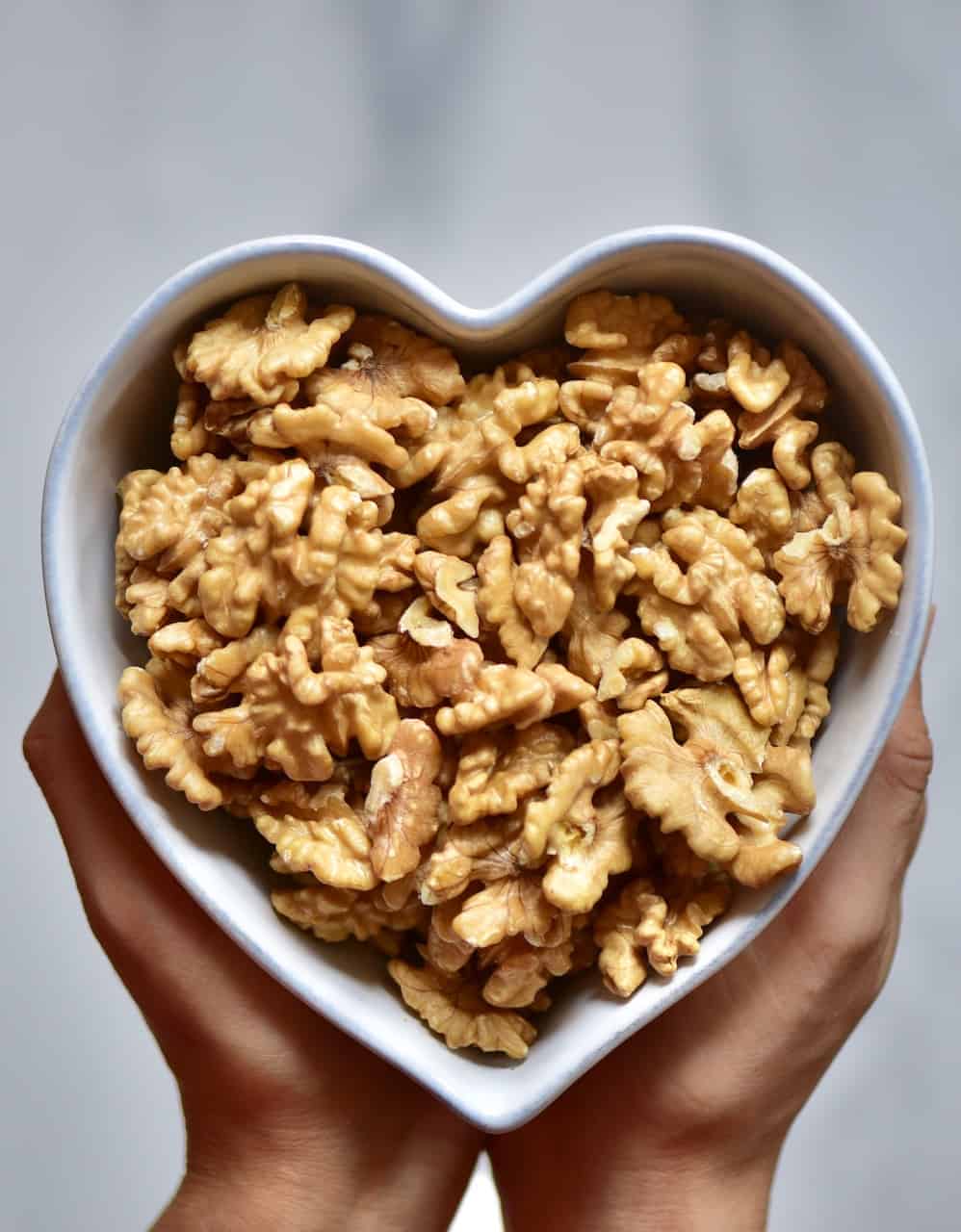 A shot of walnuts in a heart shaped bowl--ready to blend into a nut butter