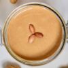 Top view of peanut butter with three peanuts in jar