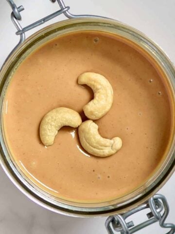 Top view of Cashew Butter and three cashews in a jar