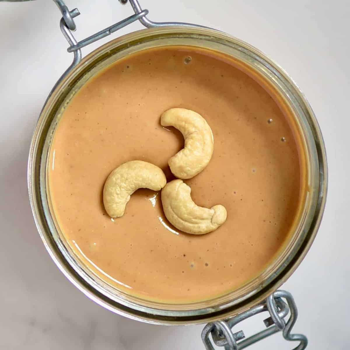 Top view of Cashew Butter and three cashews in a jar