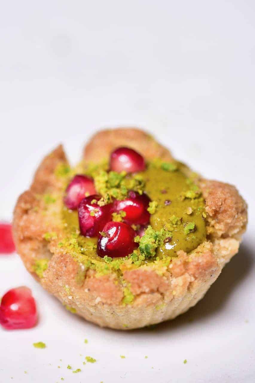One almond & pistachio thumbprint cookie with pomegranate seeds