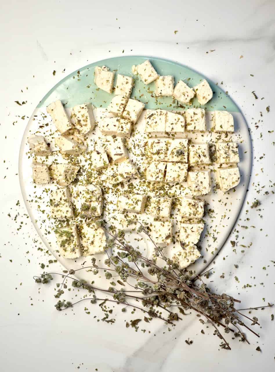 A Simple Tangy, Herby Vegan Feta Cheese Recipe. A wonderfully crumbly dairy-free cheese that's perfect for salads and topping all sorts of dishes.