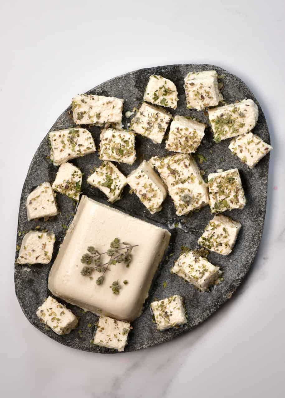 A Simple Tangy, Herby Vegan Feta Cheese Recipe. A wonderfully crumbly dairy-free cheese that's perfect for salads and topping all sorts of dishes.