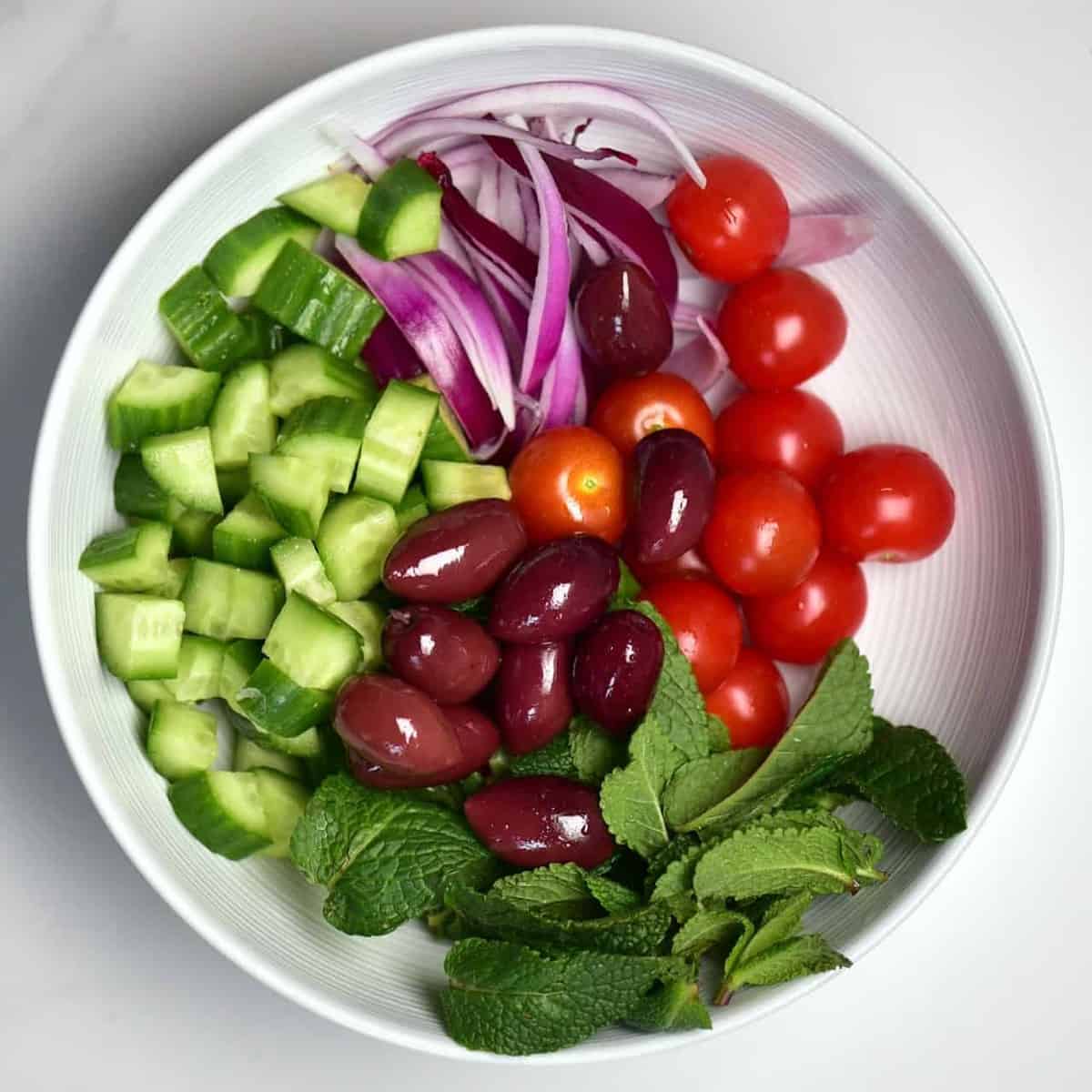 tomato, olives, red onion, cucumber and mint in a bowl