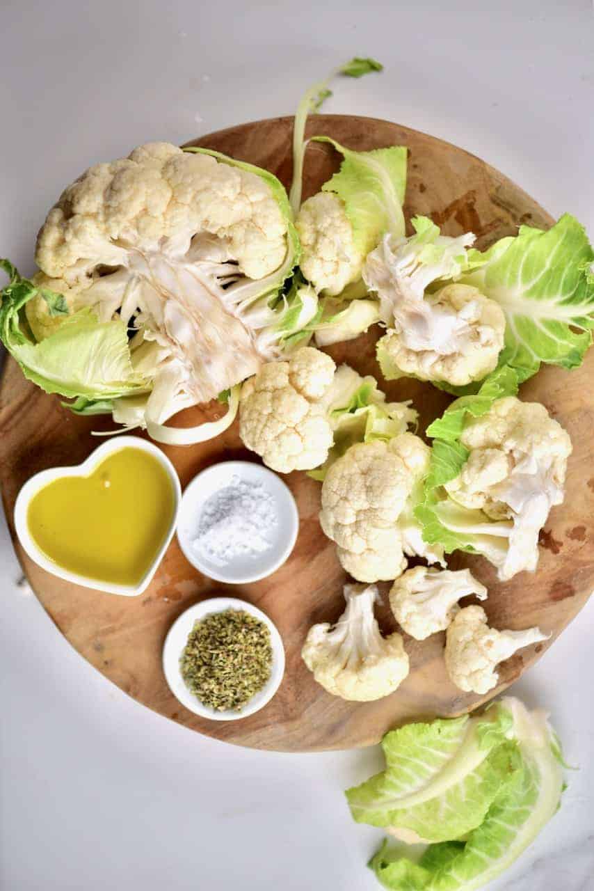 the ingredients for oregano oven baked cauliflower on a chopping board