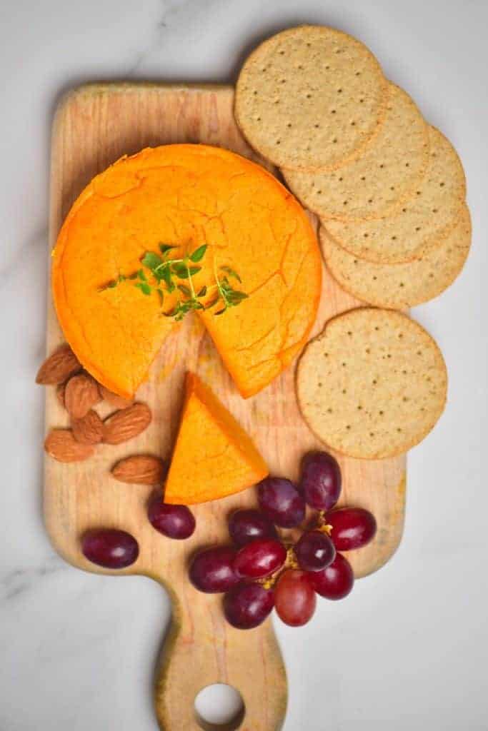 Homemade vegan cheddar cheese served with grapes, almonds and crackers
